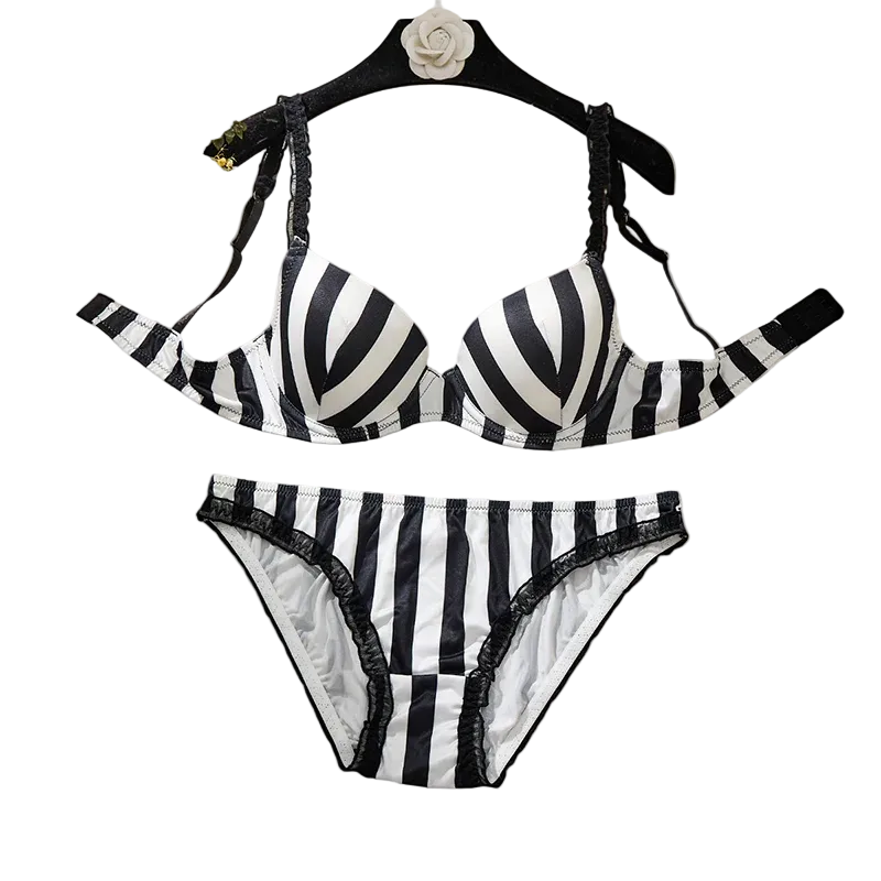 Black and white striped bikini set with lace trim, displayed on a black hanger against a solid beige background.