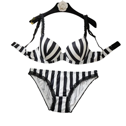 Black and white striped bikini set with lace trim, displayed on a black hanger against a solid beige background.