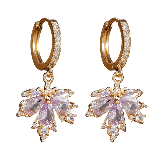 Gold hoop earrings with pink gemstones on a brown surface