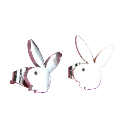 A pair of silver bunny-shaped stud earrings on a textured pink background.