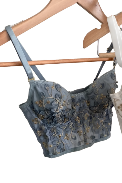 Two embroidered bras hanging on a rack against a neutral background