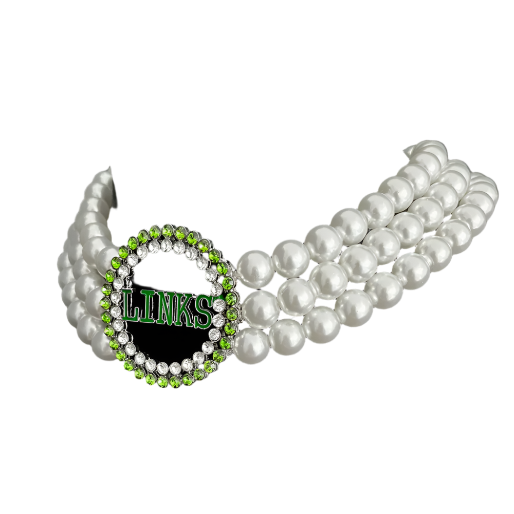 Pearl necklace with a green and silver 'LINKS' brooch on a black background