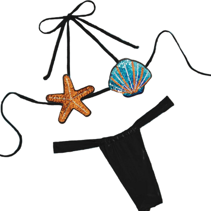 Black bikini with starfish and shell decorations on a beige fabric background
