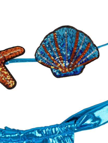 Sequined shell patch on a blue garment with a beige woven background