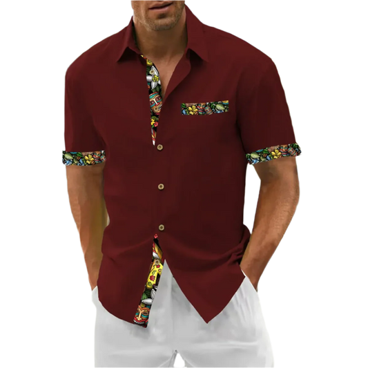 Man wearing a maroon shirt with colorful trim on a beach