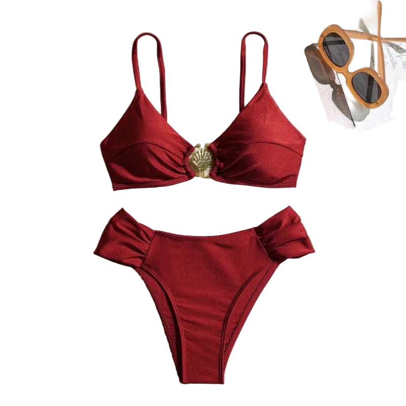Red bikini set on a textured surface with sunglasses and a magazine in the background.