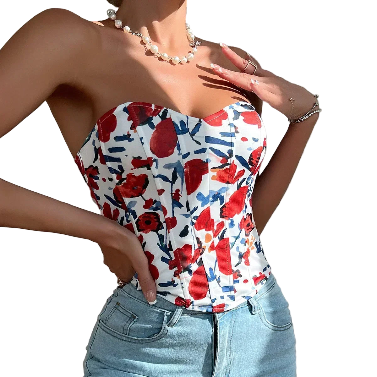 Woman wearing a strapless top with red floral pattern and light blue jeans against a neutral background