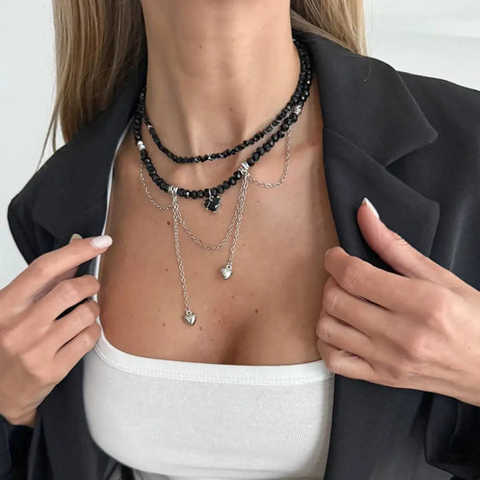 Person wearing multiple necklaces with a plain background