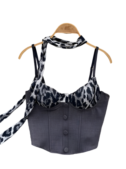 Black halter top with leopard print straps on a hanger against a floral and fur background.