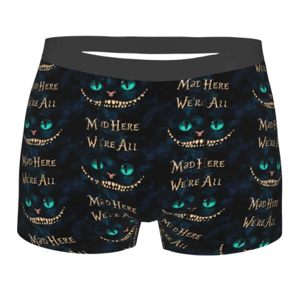 boxer shorts featuring the Cheshire Cat design from Alice in Wonderland, with glowing turquoise eyes and distinctive grinning teeth illuminated against a dark background.