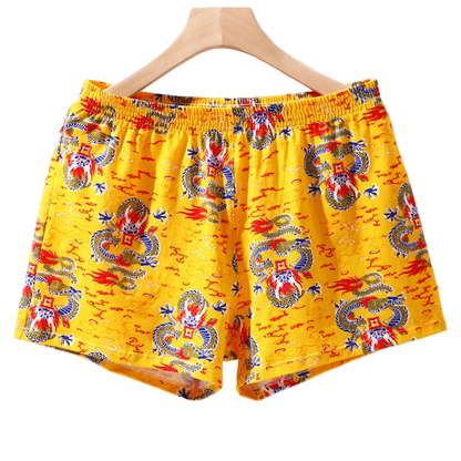 Yellow shorts with dragon pattern on a hanger against a white background