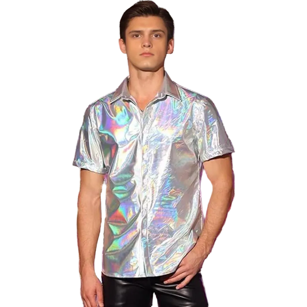 A man wearing a short-sleeve iridescent holographic button-up shirt and black pants, standing in front of a shiny silver and purple tinsel curtain backdrop.