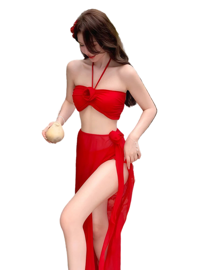 Woman in a red bikini and sarong standing against a stone wall with ocean view
