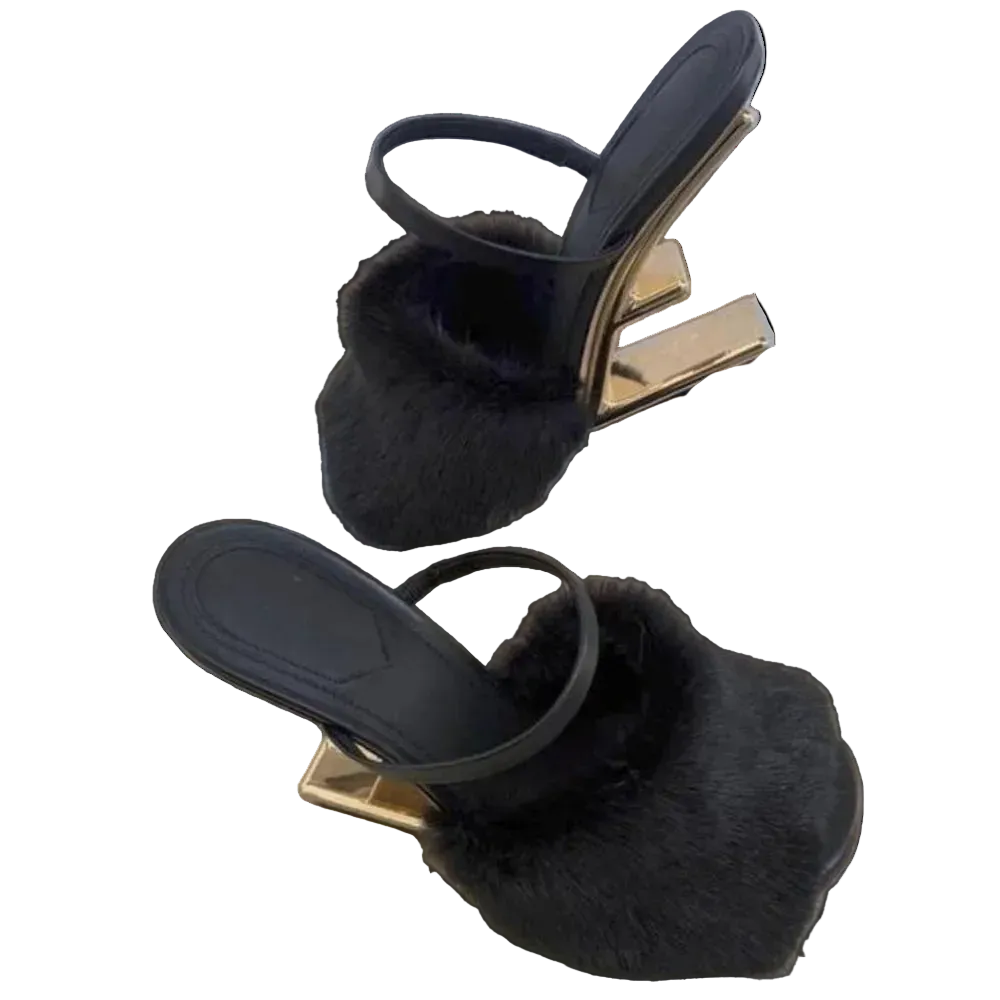 Black sandals with fur details on a gold platform on a wooden surface.