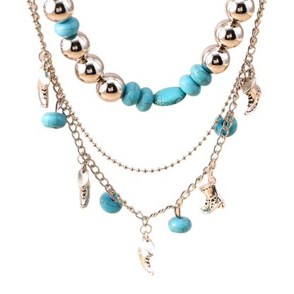 Layered necklace with turquoise beads and silver charms on a beige background