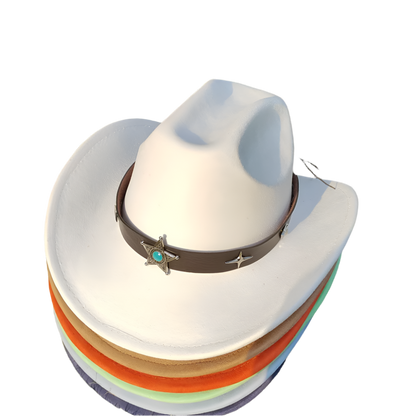 White cowboy hat with a brown band featuring star designs on a grassy background.
