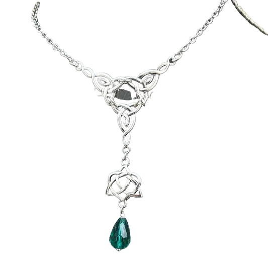A silver-toned Celtic knot lariat necklace with a teardrop-shaped green gemstone pendant, displayed on a gray fabric jewelry bust.