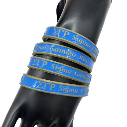 Stack of blue and gold 'Sigma Gamma Rho' bracelets on a black mannequin arm against a white background.