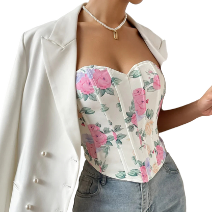 Person wearing a floral top and white blazer with a neutral background
