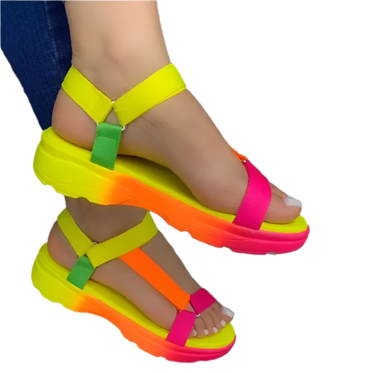 Neon colorful sandals on a dark pavement background