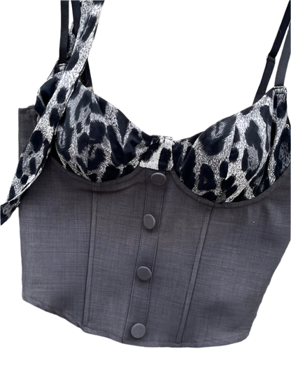 Gray corset with leopard print trim on a textured surface