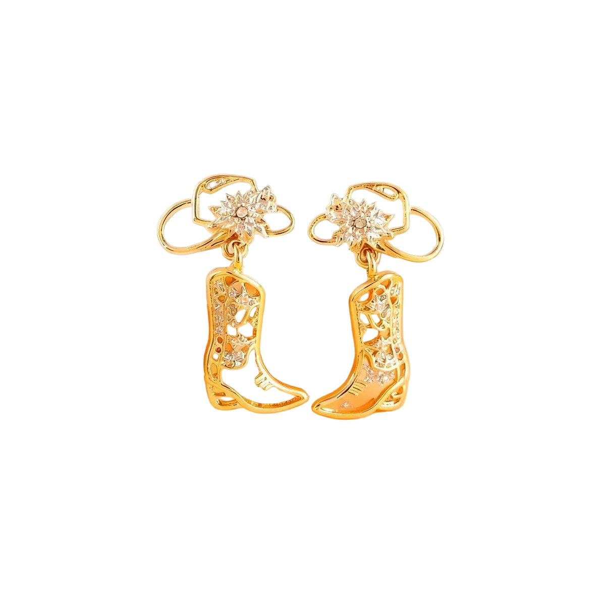 A pair of gold-toned cowboy boot earrings with clear rhinestone embellishments, displayed on a soft beige and peach background.