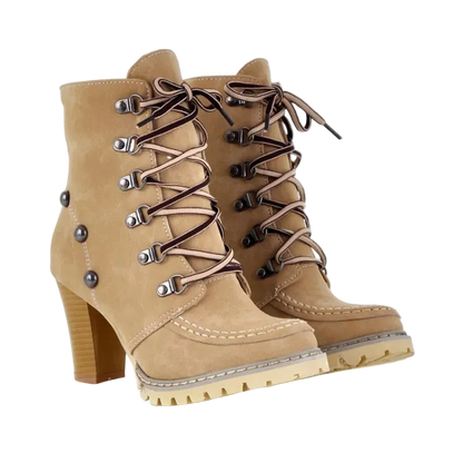 A pair of beige suede lace-up ankle boots with a chunky block heel, silver metal eyelets, and brown laces, shown on a white background.