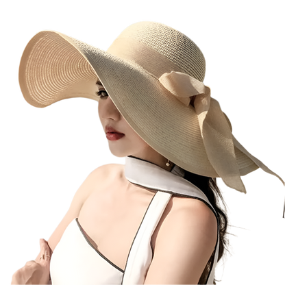 Woman wearing a large beige sun hat with a bow on a beach