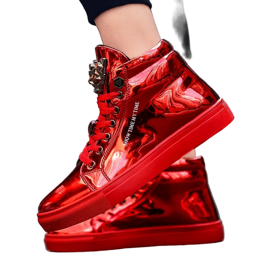 A pair of shiny metallic red high-top sneakers with decorative metal eyelets and white text reading 'STAY IN MY TIME' on the side, shown worn with one shoe lifted over the other on an outdoor street background.