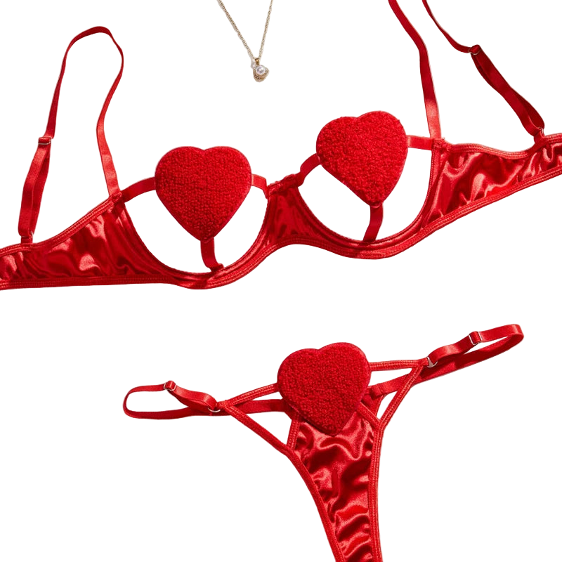 Red heart-shaped lingerie set on a white surface with flowers and jewelry.