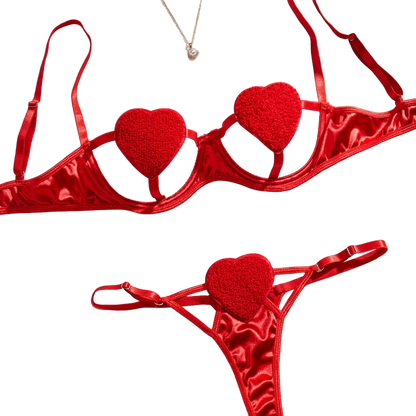 Red heart-shaped lingerie set on a white surface with flowers and jewelry.