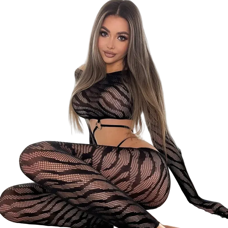 Woman wearing a black fishnet outfit sitting on a bed.