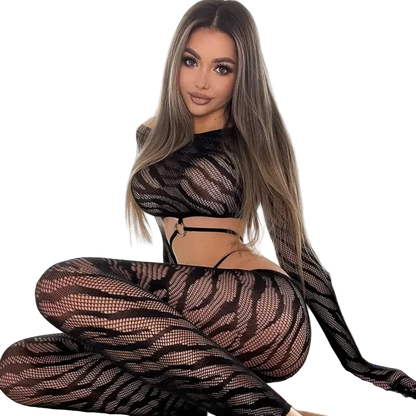Woman wearing a black fishnet outfit sitting on a bed.