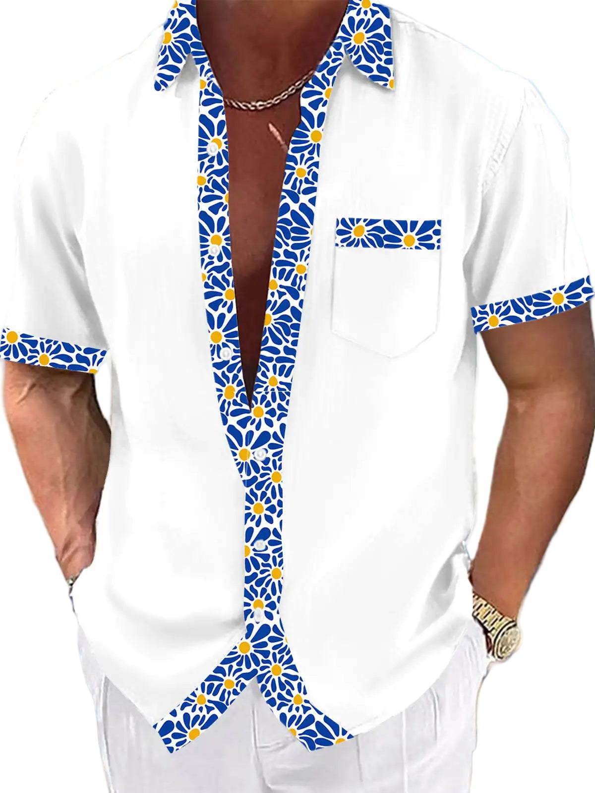White shirt with blue floral patterns worn by a person on a beach.
