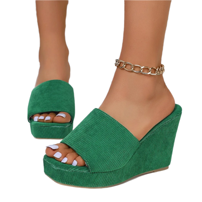 Green wedge sandals worn with a glittery background