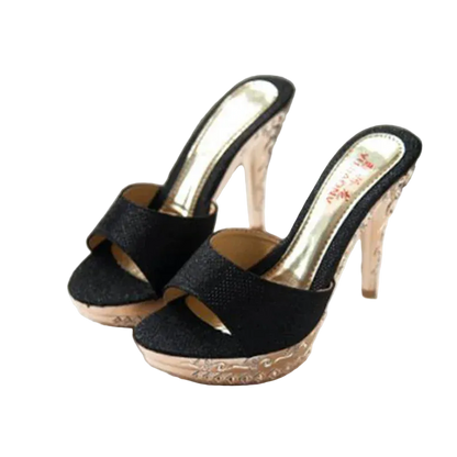 Black high-heeled shoes with rose gold accents on a white surface.
