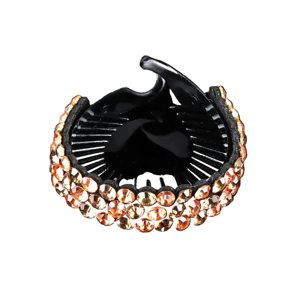 A black hair claw clip embellished with rows of rose gold rhinestones, shown on a reflective black background.