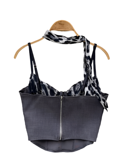 Black tank top with tie detail on a hanger against a floral and textured background