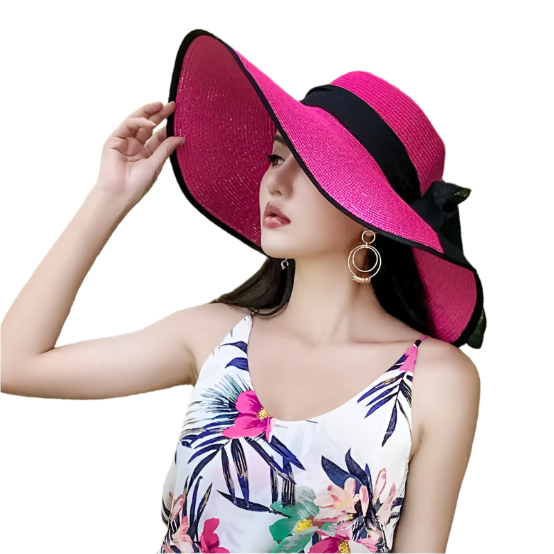 Woman wearing a bright pink sun hat with a black band outdoors.