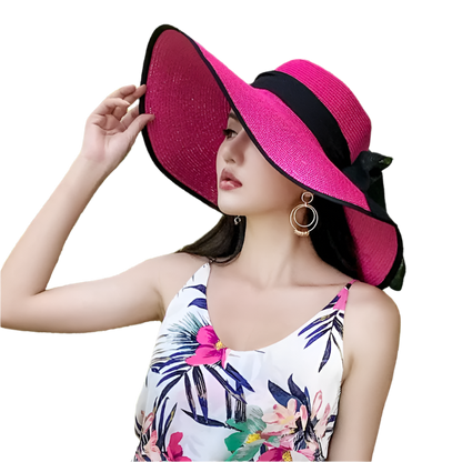 Woman wearing a bright pink sun hat with a black band outdoors.