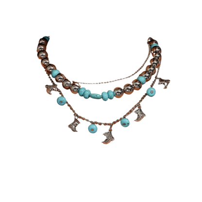 Necklace with turquoise beads and charms on a person wearing a white top.