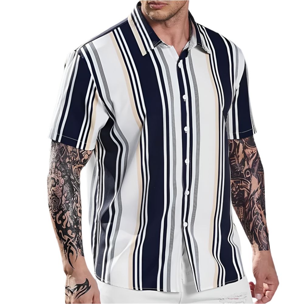 Man wearing a striped shirt with tattoos on arms standing outdoors.