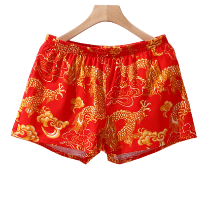 Red shorts with gold dragon pattern on a hanger against a white background