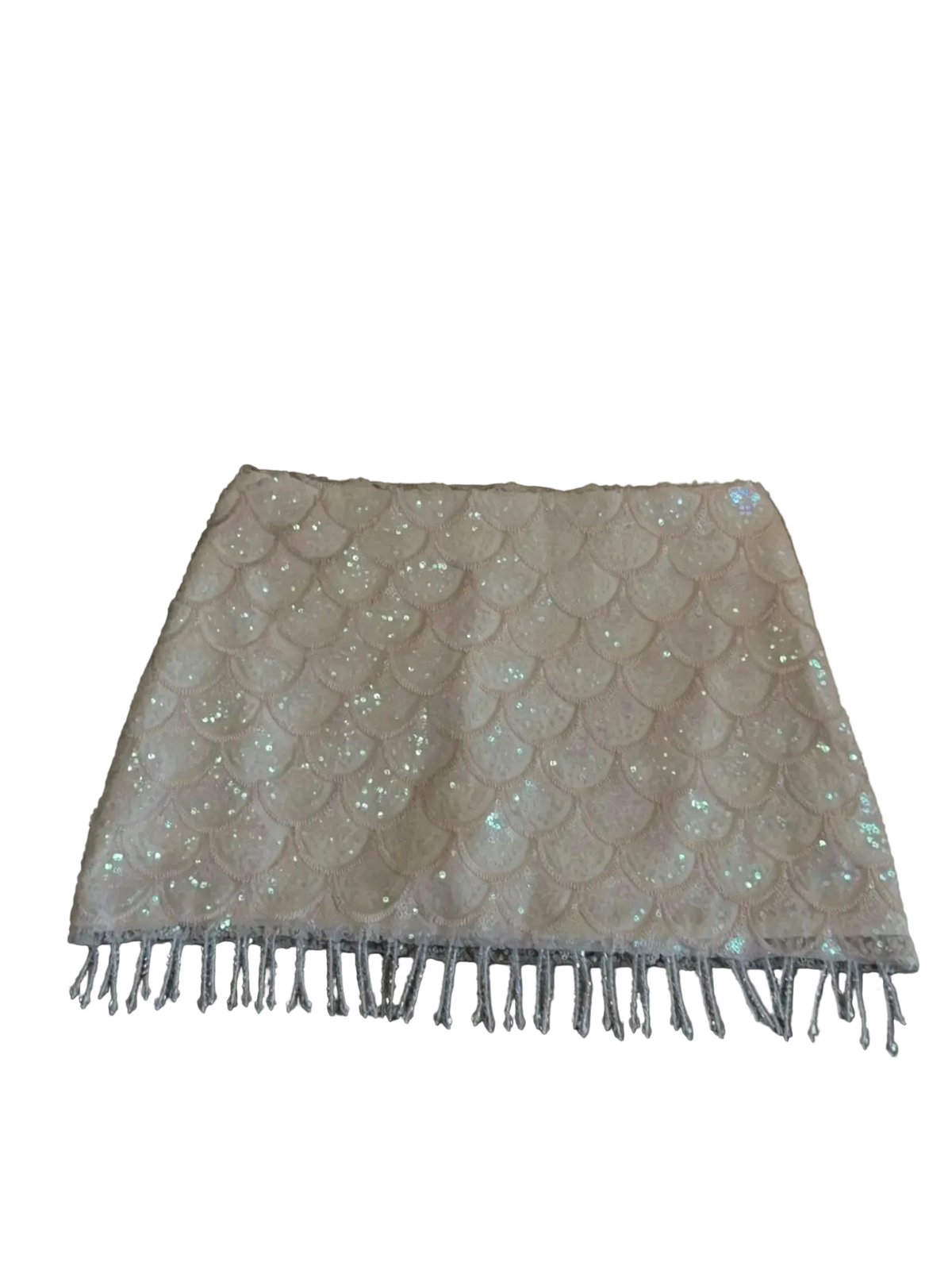A light beige or cream sequined skirt with a scalloped pattern and fringe trim, laid flat on a gray upholstered sofa.