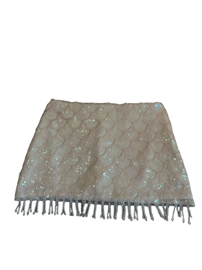 A light beige or cream sequined skirt with a scalloped pattern and fringe trim, laid flat on a gray upholstered sofa.
