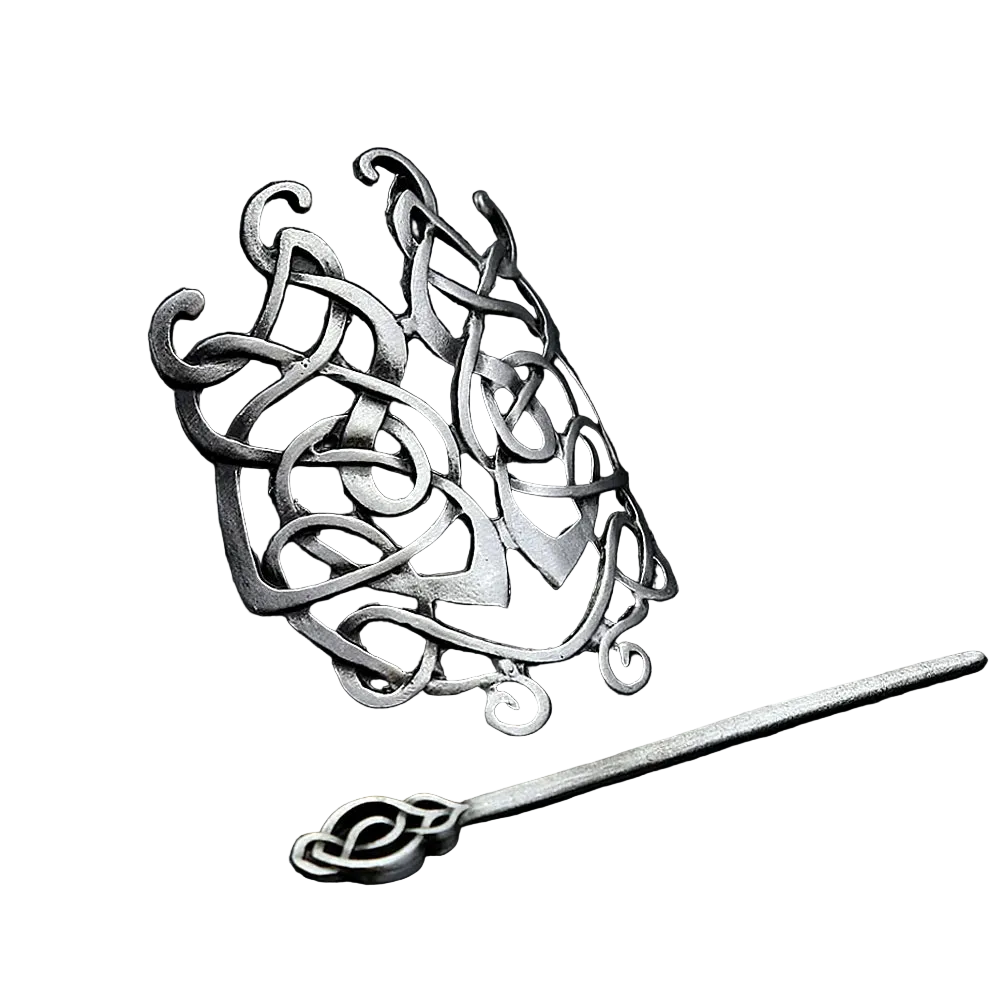 Silver hairpin with intricate designs on a dark textured surface
