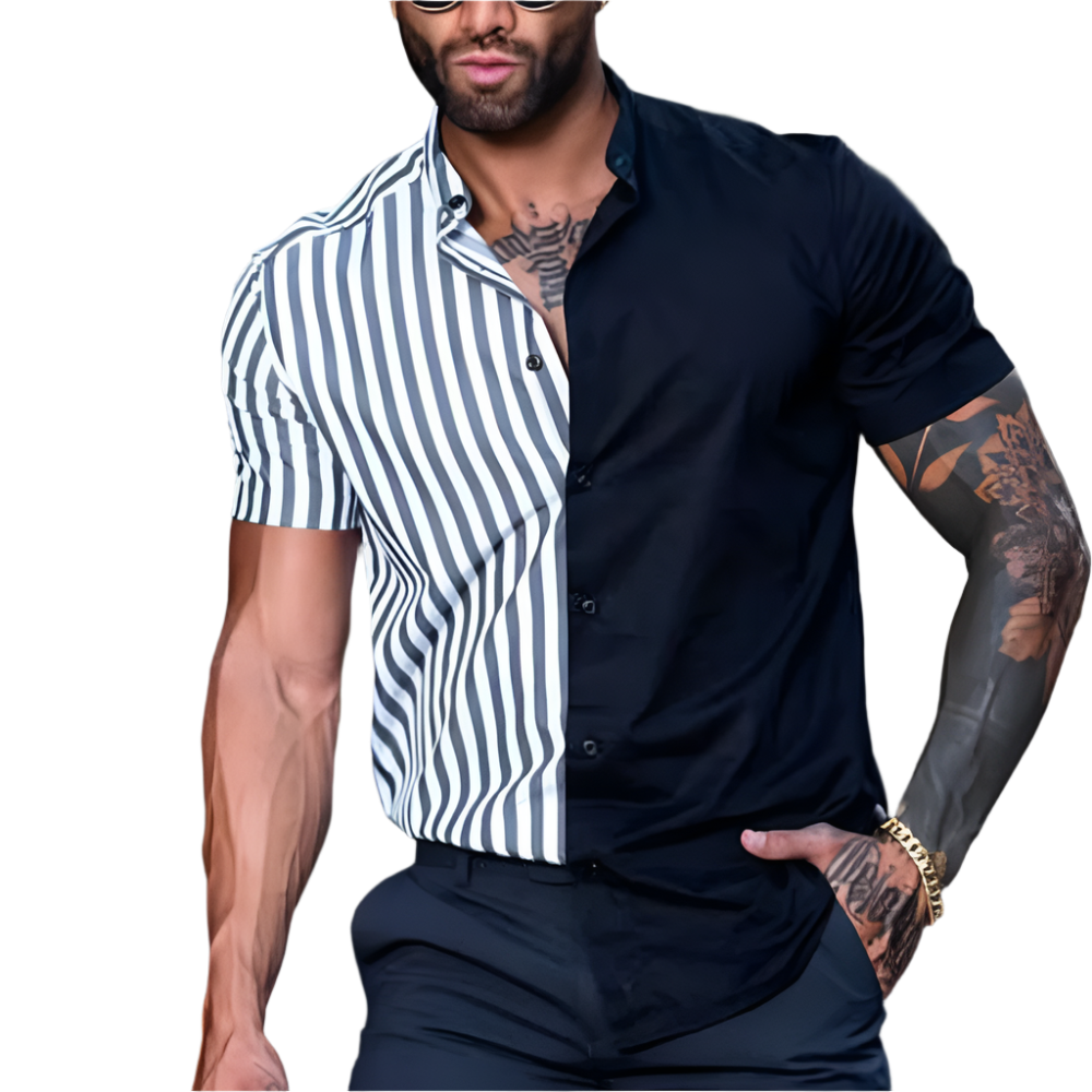 Man wearing a black and white striped shirt over a black shirt with tattoos on arms, sitting against a blurred background.