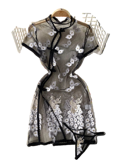 Black lace dress with floral embroidery on a white textured surface