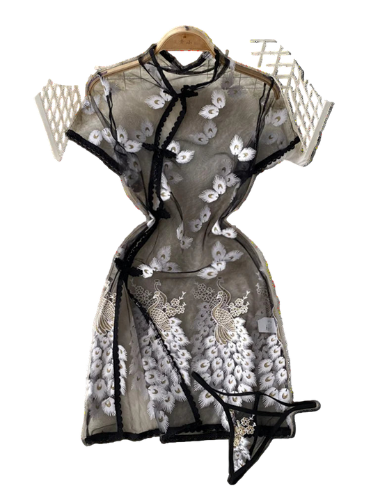 Black lace dress with floral embroidery on a white textured surface