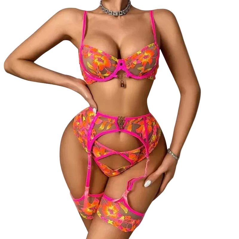 A woman modeling a bright pink and orange floral lingerie set with a matching garter belt and thigh-high stockings against a plain white background.